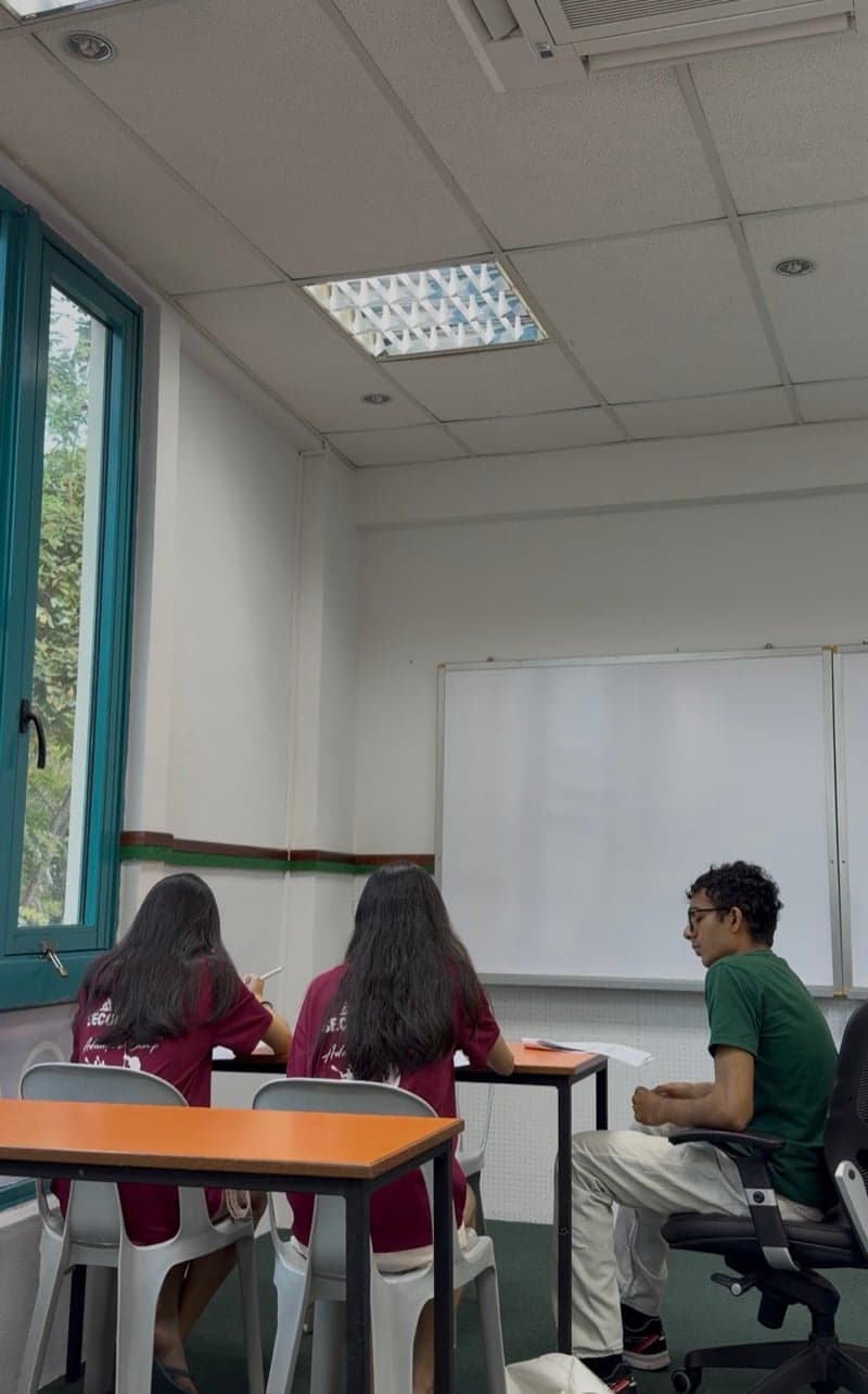 Small-group tuition class in session at Ancourage Academy Woodlands — a tutor guiding two students beside the whiteboard in our Vista Point classroom.