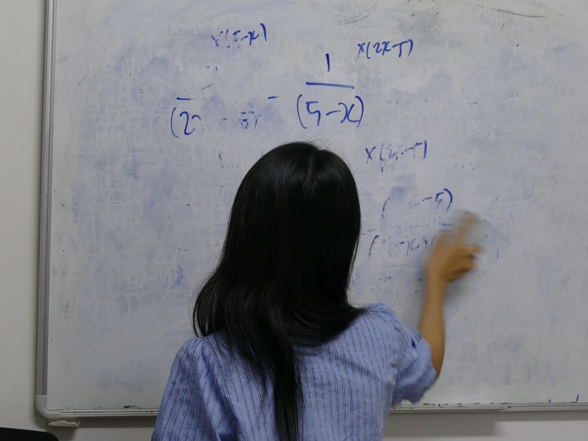 Tutor at Ancourage Academy explaining concepts on a whiteboard during a small-group lesson