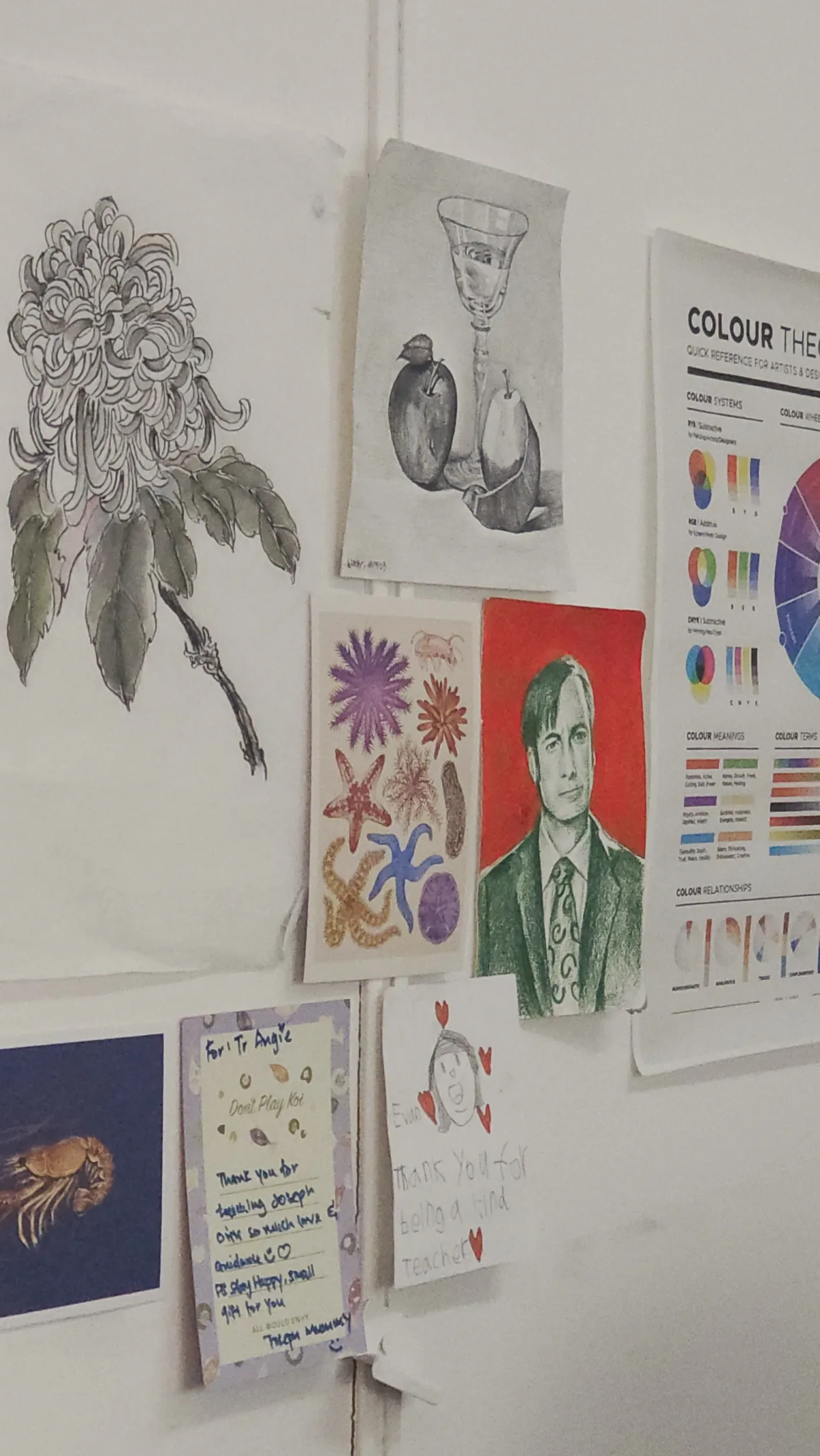 Student artwork wall at the Bishan centre with still-life drawings, paintings and a colour-theory reference chart.